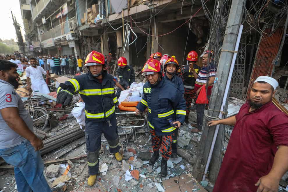 Fire officials carry away a body after an explosion, in Dhaka (Abdul Goni/AP)