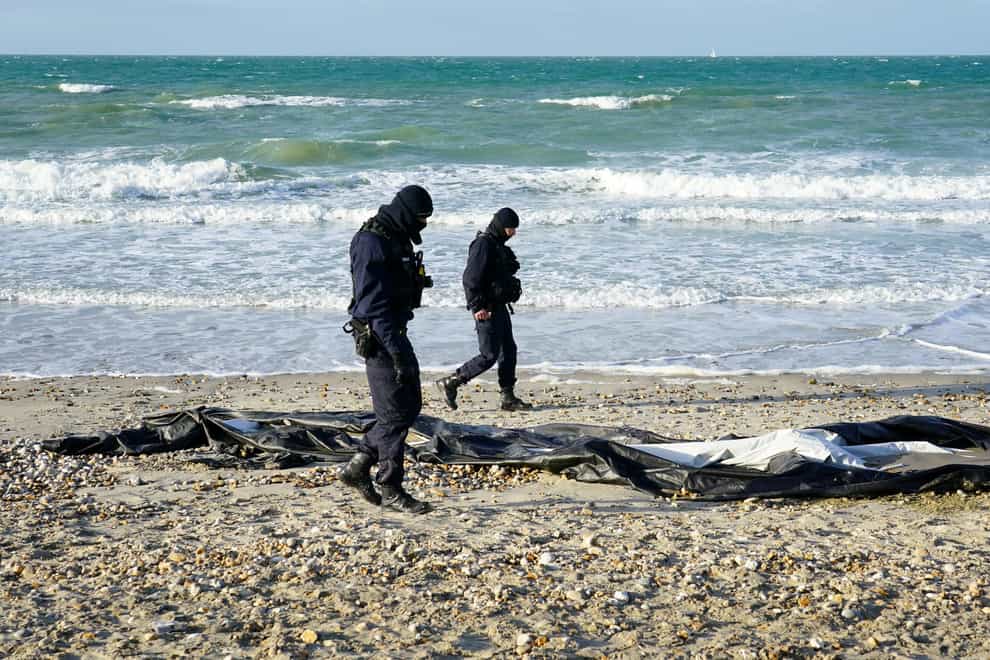 French police officers pass a deflated dinghy on the beach in Wimereux near Calais (Gareth Fuller/PA)