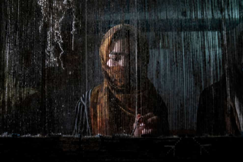 An Afghan woman weaves a carpet at a traditional carpet factory in Kabul, Afghanistan (Ebrahim Noroozi/AP)