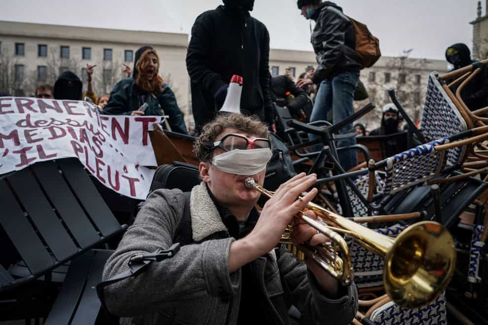 A man plays the trumpet in front of a barricade during a demonstration in Lyon (Laurent Cipriani/AP)