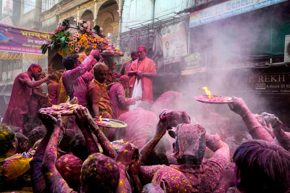 Hindu devotees with offerings make way to reach the car which carried the deity Shri Krishna during the Holi festival in Kolkata, India (Bikas Das/AP)