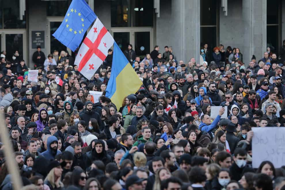 Protesters gather with Georgian, Ukrainian national and EU flags outside the Georgian parliament building in Tbilisi (Zurab Tsertsvadze/AP)