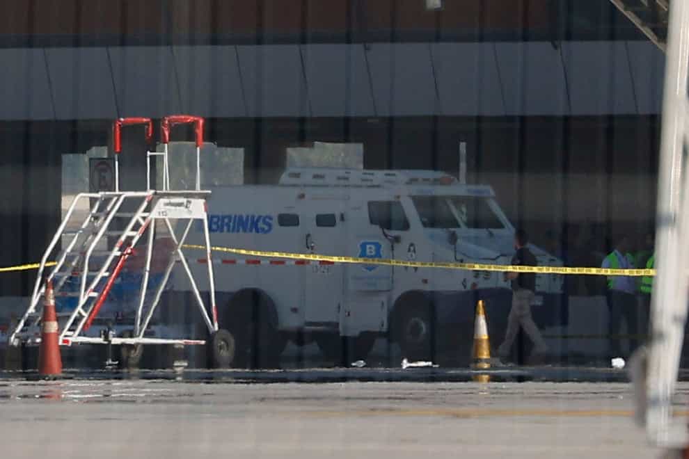 An armoured truck is cordoned off by police tape at the Arturo Merino Benitez International Airport in Santiago (Karin Pozo, Aton Chile via AP)