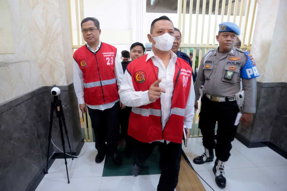 Arema FC organising committee chairman Abdul Haris, left, and the club’s security chief Suko Sutrisno, centre, walk to the courtroom to attend their sentencing hearing (Trisnadi/AP)