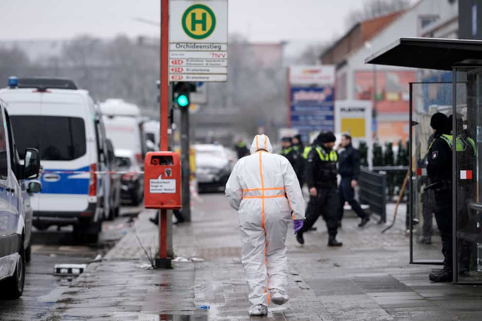 A forensic expert walks beside police outside a Jehovah’s Witness building in Hamburg (Markus Schreiber/AP)