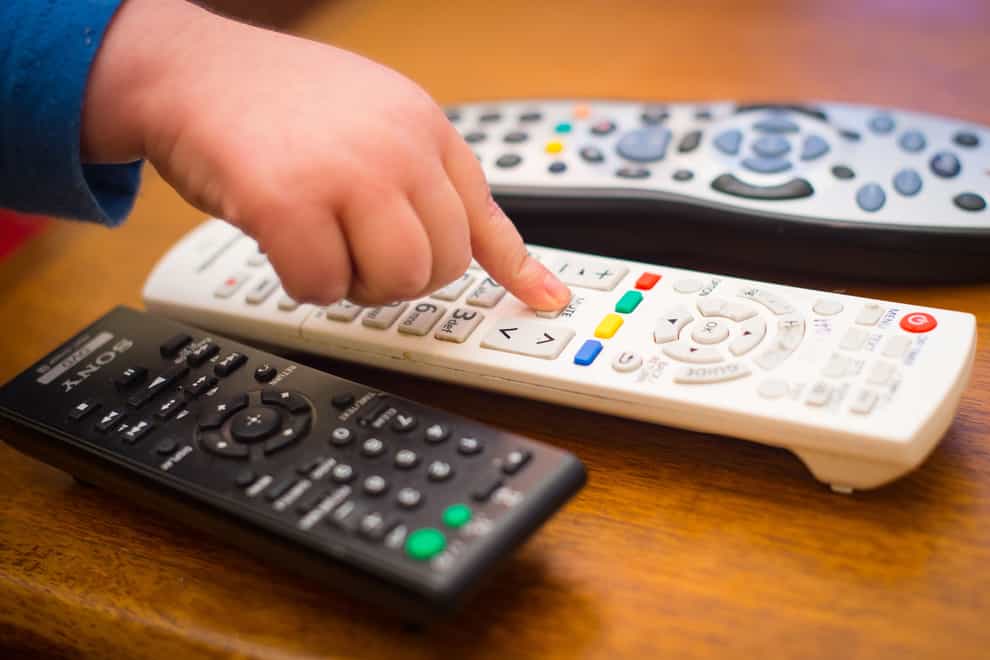 A child’s hand presses a button television remote control (Dominic Lipinski/PA)