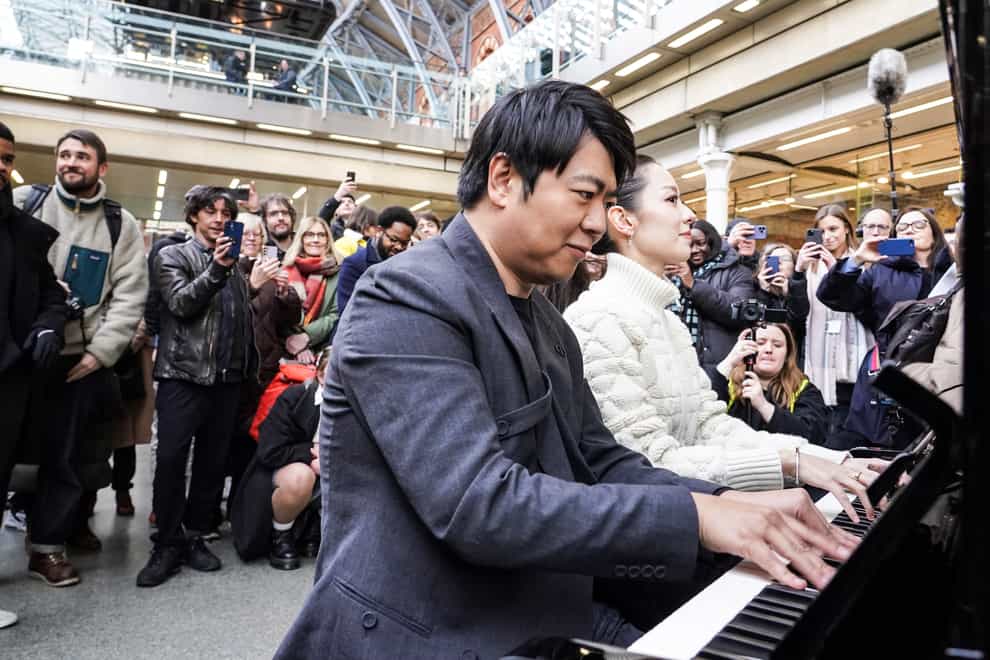Pianist Lang Lang and his wife Gina Alice Redlinger perform on a public piano at St Pancras station in London (Ian West/PA)