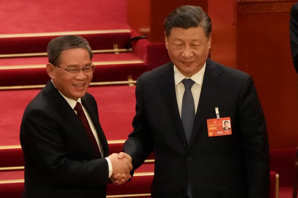 Newly elected premier Li Qiang (left) shakes hands with Chinese President Xi Jinping (AP Photo/Mark Schiefelbein)