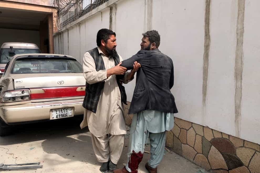 An Afghan man helps a victim after the bomb blast in Mazar-e-Sharif (Abdul Saboor Sirat/AP)
