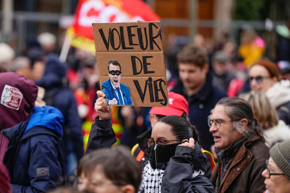 A protester holds a placard depicting a portrait of French President Macron and saying ‘life thief’ during a demonstration in Paris (Lewis Joly/AP)