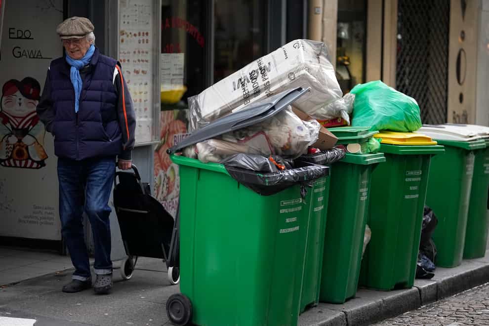 A man walks past uncollected rubbish in Paris (Michel Euler/AP)