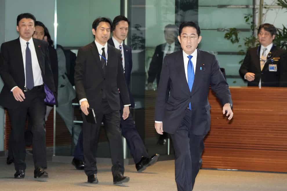 Japanese Prime Minister Fumio Kishida arrives without wearing a face mask at his office in Tokyo (Kyodo via AP)