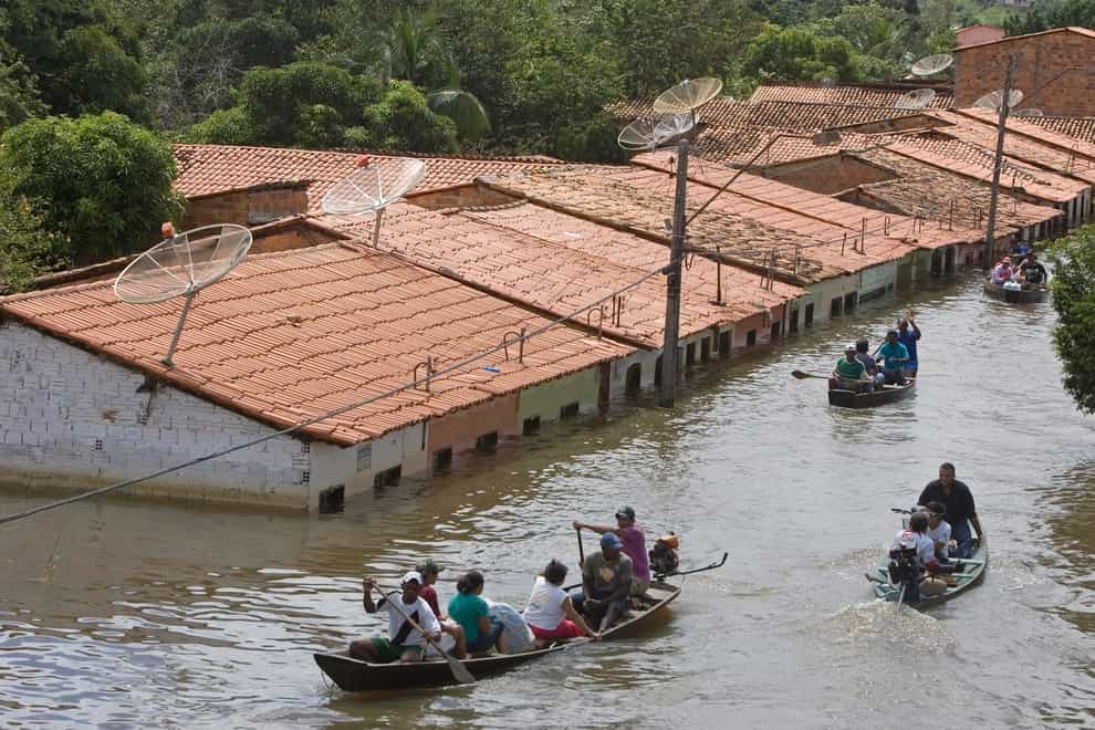 People travel by boat in a flooded street in Trizidela do Vale in the state of Maranhao, Brazil (Andre Penner/AP)