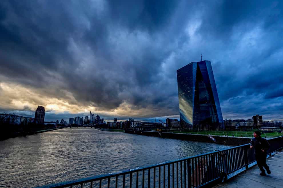 Dark clouds drift over the city as a man runs over a bridge near the European Central Bank in Frankfurt, Germany, Friday, March 10, 2023. (AP Photo/Michael Probst)