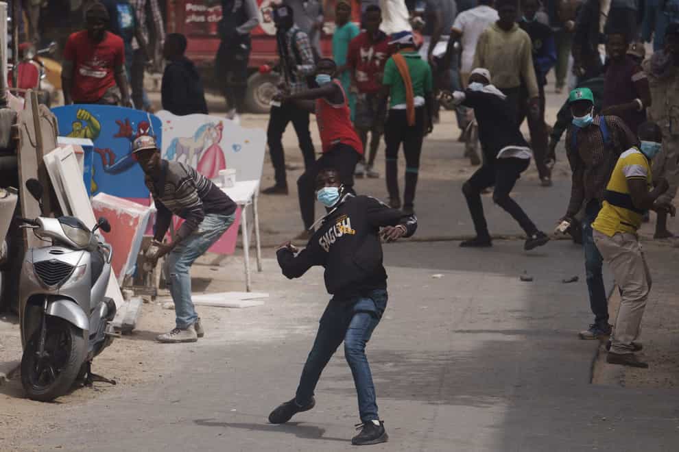 A demonstrator throws a rock during clashes with riot police after the opposition leader’s Ousmane Sonko left the tribunal in Dakar, Senegal, Thursday, Feb. 16, 2023. Police in Senegal smashed out the windows of the Sonko’s car and forced him from the vehicle after he appeared in court. (AP Photo/Leo Correa)