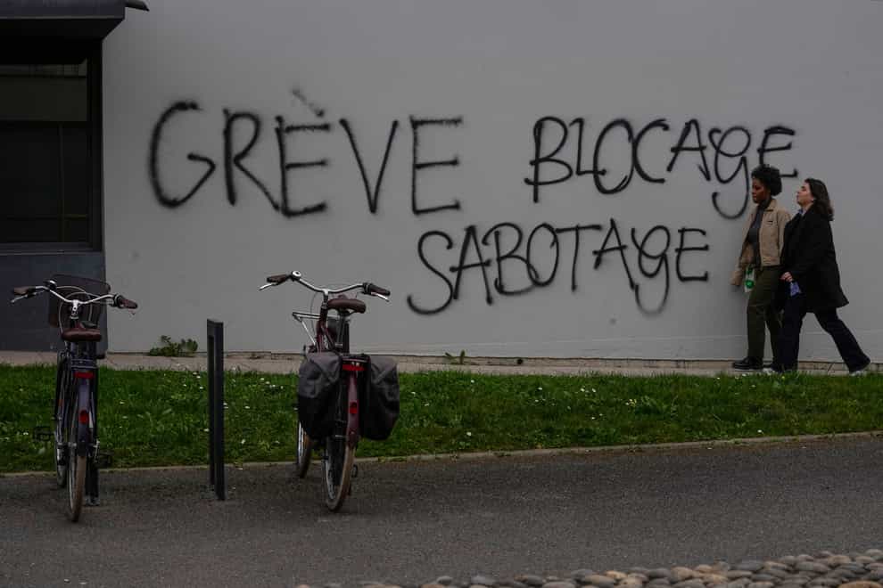 Students walk past a graffiti reading “strike, blocking, sabotage” at the closed Nanterre university near Paris (Michel Euler/AP)