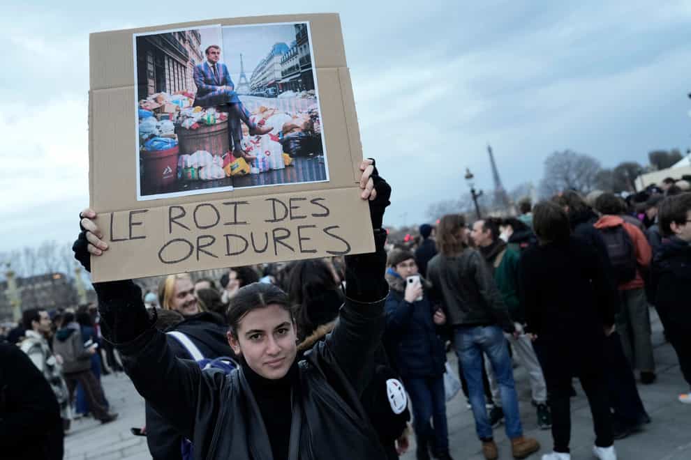 A placard depicts Emmanuel Macron and reads ‘king of rubbsih’ (Lewis Joly/AP)