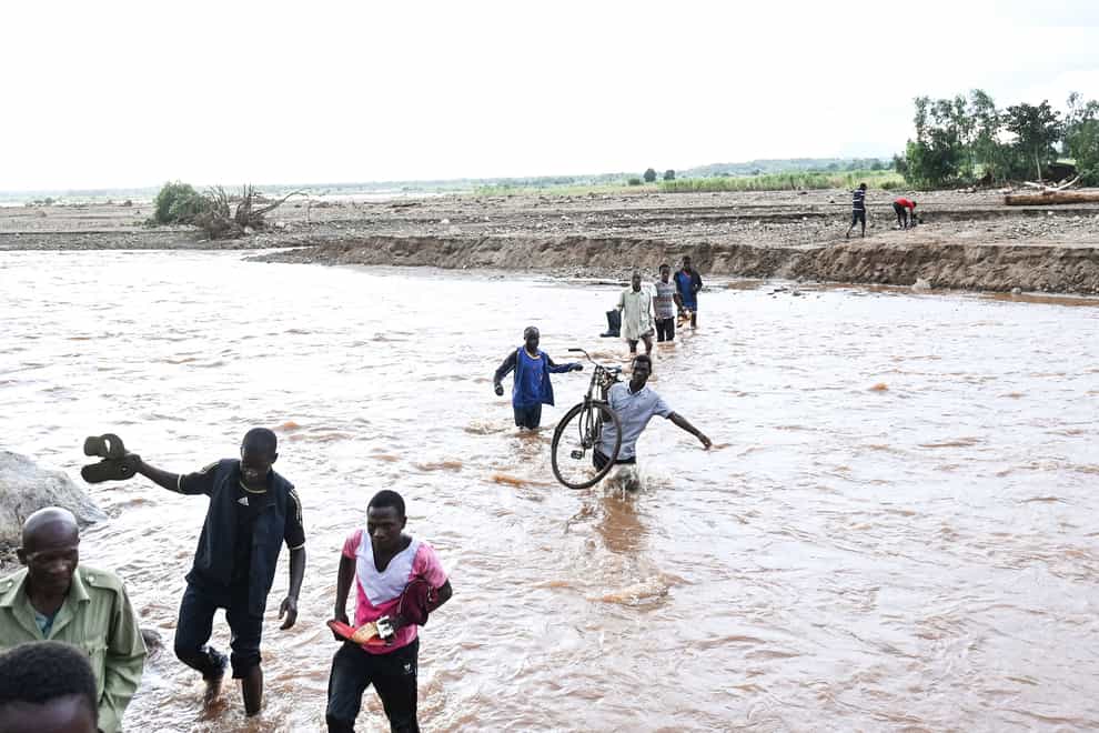 People wade through flood waters caused by last week’s heavy rains caused by Tropical Cyclone Freddy in Phalombe, southern Malawi Saturday, March 18, 2023. Authorities are still getting to grips with destruction in Malawi and Mozambique with over 370 people confirmed dead and several hundreds still displaced or missing. (AP Photo/Thoko Chikondi)