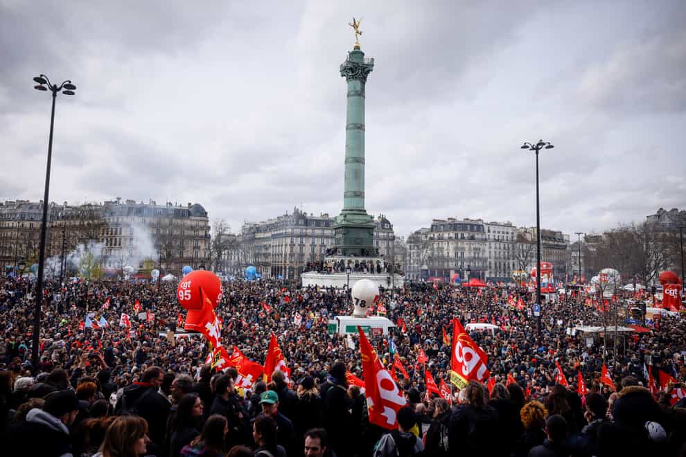 Protesters gathering at Place de la Bastille during a rally in Paris, Thursday, march 23, 2023. French unions are holding their first mass demonstrations Thursday since President Emmanuel Macron enflamed public anger by forcing a higher retirement age through parliament without a vote. Placard left, depicting French President Emmanuel Macron that reads, “my pension before yours.”(AP Photo/Thomas Padilla)