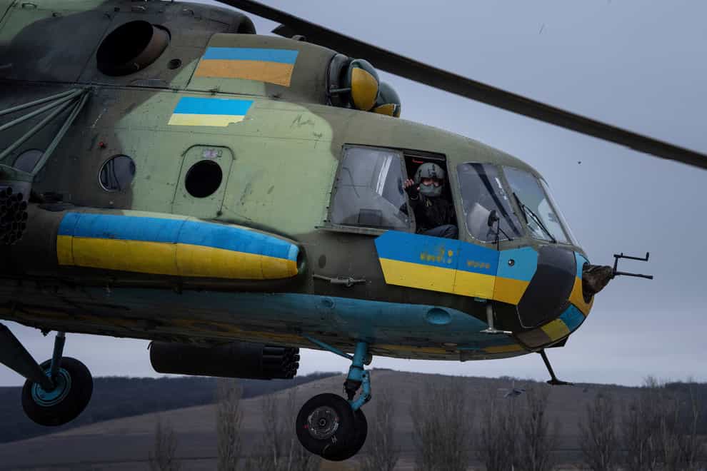 A Ukrainian pilot waves to his comrades from an Mi-8 combat helicopter during a combat mission in Donetsk region, Ukraine (Evgeniy Maloletka/AP)