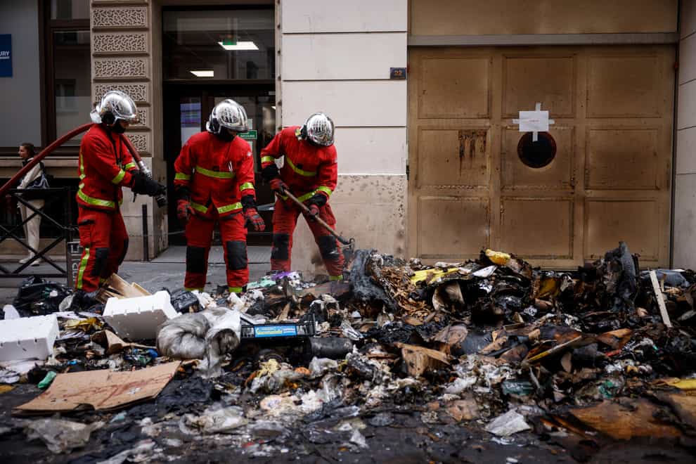 Firefighters controlling the remains of a rubbish fire from Thursday night’s protests in Paris against the retirement Bill (Thomas Padilla/AP)