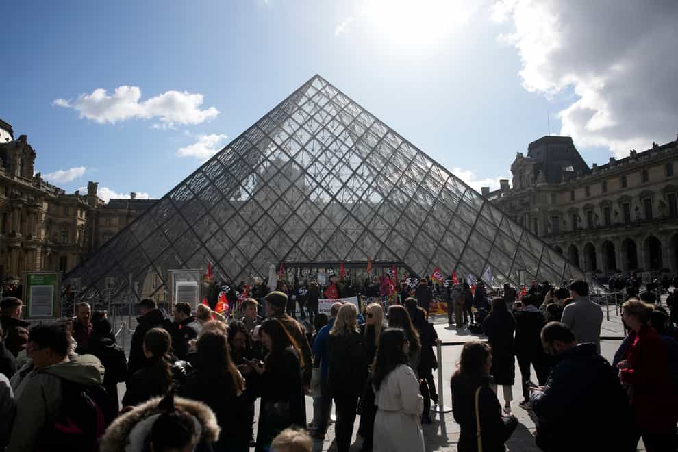Visitors wait as workers of the culture industry demonstrate outside the Louvre museum (AP)
