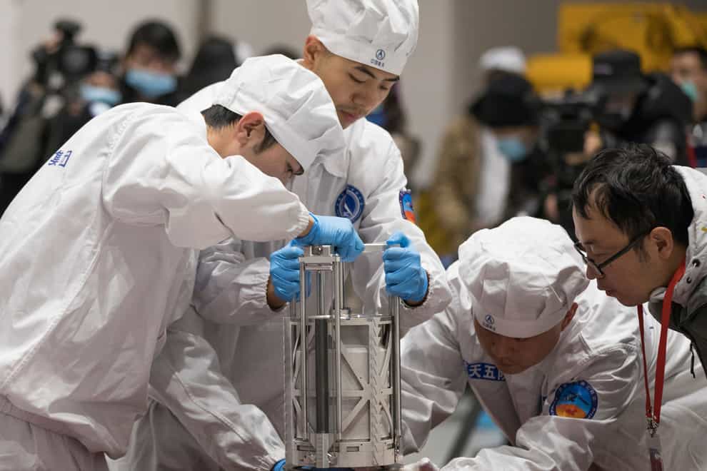 Technicians prepare to weigh a container carrying moon samples retrieved by China’s Chang’e 5 lunar lander (Jin Liwang/Xinhua/AP)