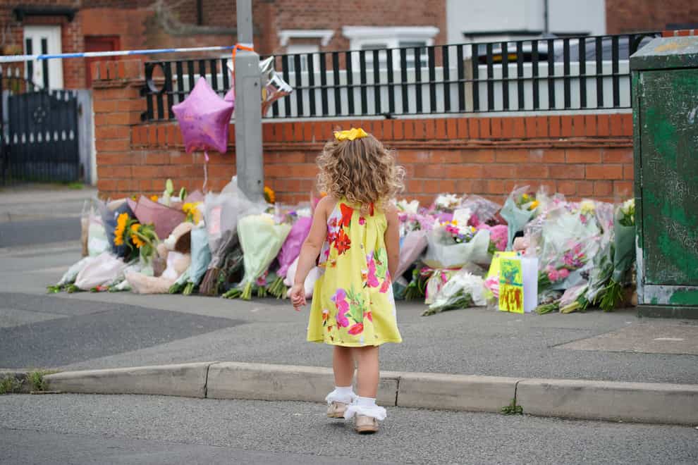 A young girl lays a tribute in Kingsheath Avenue, Dovecot, Liverpool (Peter Byrne/PA)