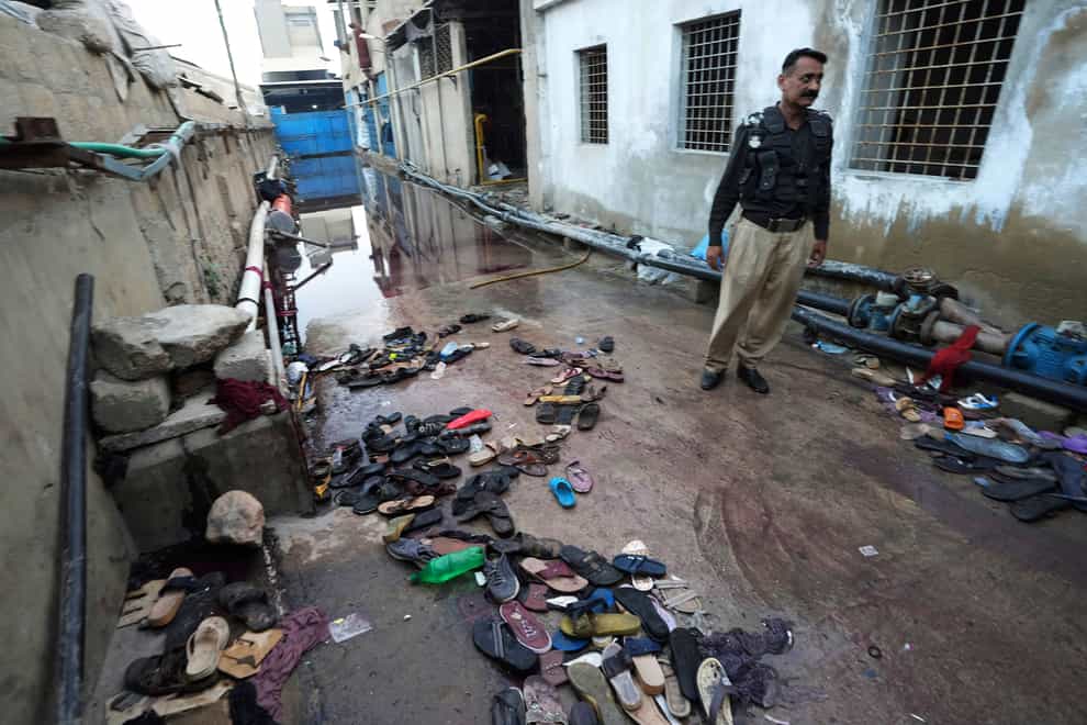 A police officer examines the site of stampede, in Karachi, Pakistan, Friday, March 31, 2023. Several people were killed in the deadly stampede at a Ramadan food distribution center outside a factory in Pakistan’s southern port city of Karachi, police and rescue officials said. (AP Photo/Fareed Khan)