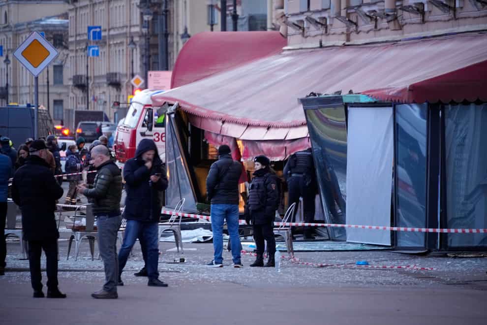 Russian investigators and police officers stand at the site of an explosion at a cafe in St Petersburg (AP)