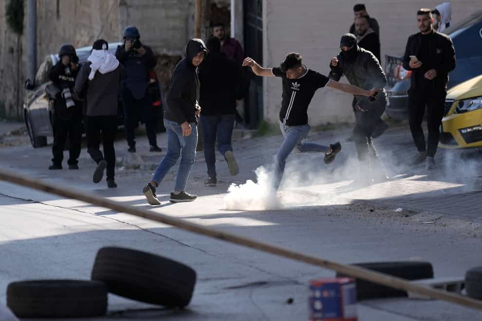 A Palestinian demonstrator kicks a tear gas canister during clashes with Israeli forces (AP)