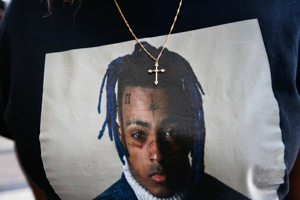 A fan wears a cross around her neck dangling on a T-shirt in remembrance before she enters a memorial for the rapper XXXTentacion in Florida (Brynn Anderson/AP)
