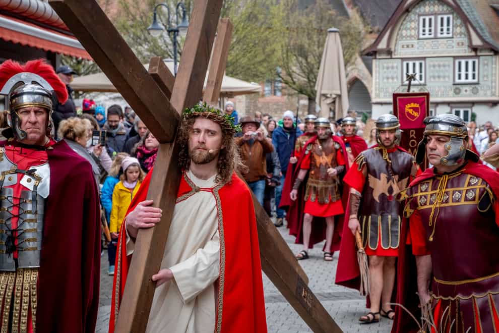 An amateur actor performing as Jesus, centre, carries a cross during the Good Friday procession in Bensheim, Germany, Friday, April 7, 2023. Around 90 amateur actors and actresses in historical costumes parade through downtown Bensheim and re-enact the Stations of the Cross. The procession is organized by the association “Bensheim Italian Families and German Friends”. (AP Photo/Michael Probst