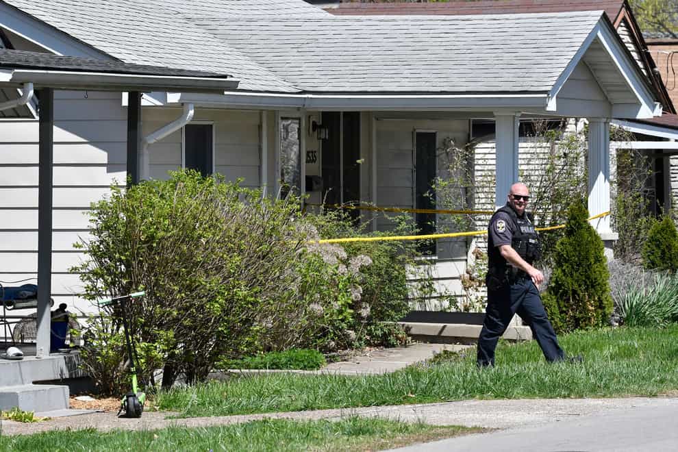 A Louisville Metro Police officer walks outside the home of the gunman in the Camp Taylor neighbourhood in Louisville (Timothy D Easley/AP)