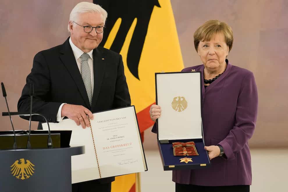 German President Frank-Walter Steinmeier, left, presents the Grand Cross of the Order of Merit of the Federal Republic of Germany in a special design to former chancellor Angela Merkel during a reception at Bellevue Palace in Berlin, Germany (Markus Schreiber/AP)