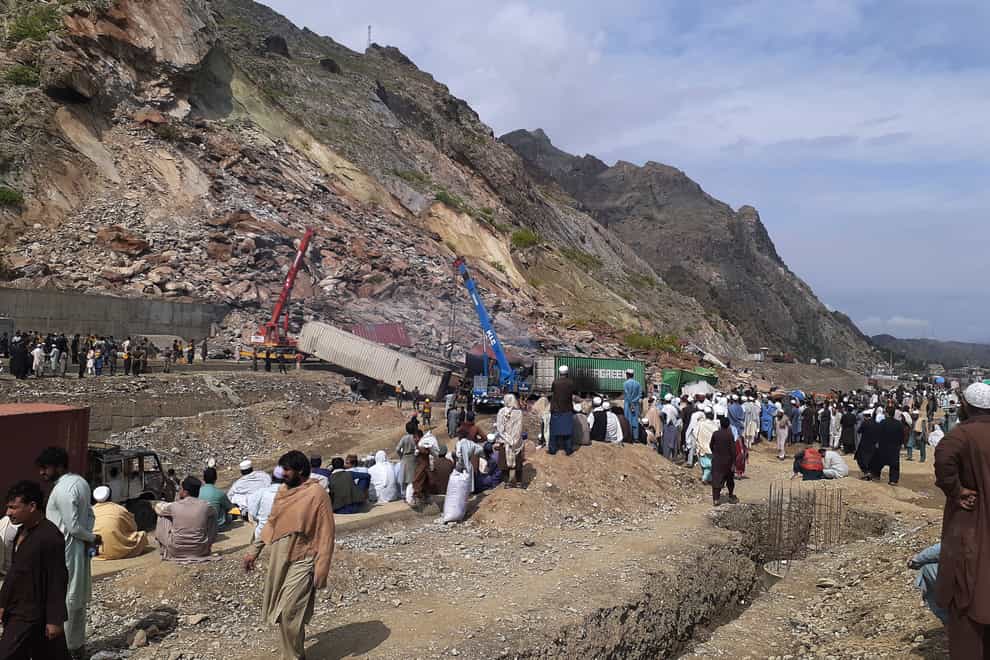 Authorities use heavy machines to search for survivors and clear the rubble following a landslide (Muhammad Sajjad/AP)