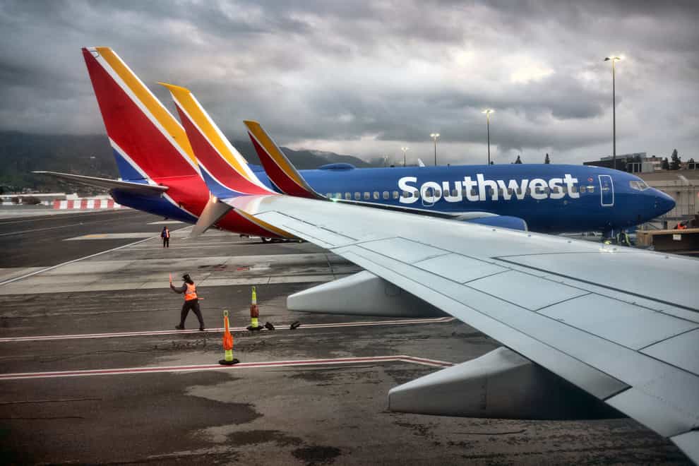A Southwest Airlines ground crew directs a plane out of the terminal. The company suffered flight delays due to technical issues (Richard Vogel/AP/PA)