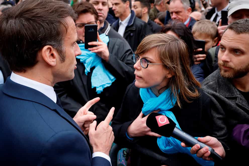 French President Emmanuel Macron argues with a person opposed to the pension reform in Selestat, eastern France (Ludovic Marin, Pool via AP)
