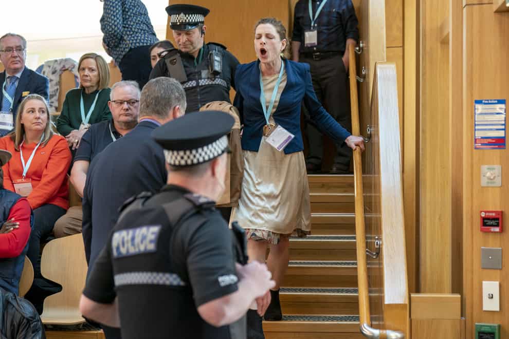 A protester is removed from the public gallery in the main chamber during First Minister’s Questions at the Scottish Parliament (Jane Barlow/PA)