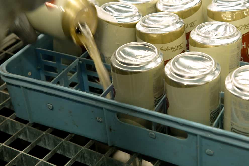 In this image provided by Comite Champagne, a worker pours out the contents of cans of Miller High Life beer prior to them being crushed at the Westlandia plant in Ypres, Belgium, Monday, April 17, 2023. Belgian customs have destroyed more than 2,000 cans of Miller High Life advertised as the ″Champagne of beers” at the request of houses and growers of the bubbly beverage. (Comite Champagne via AP)