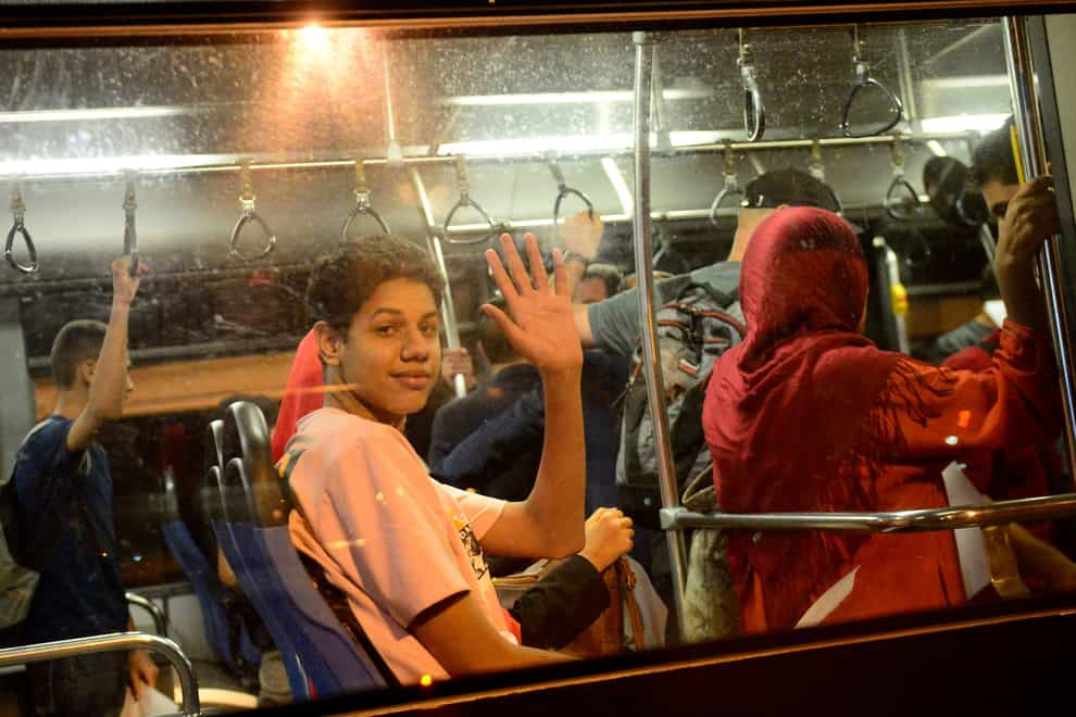 People wave from a bus after arriving in a military plane from Khartoum at the Houari-Boumediene airport in Algiers (Amine/AP)