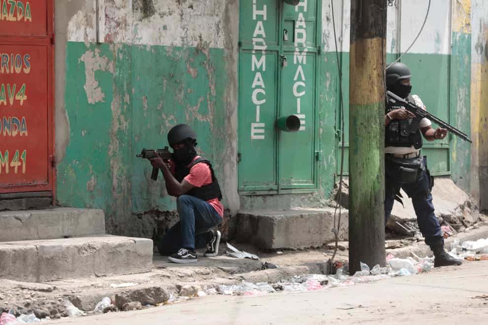 Police officers take cover during an anti-gang operation in the Portail neighbourhood of Port-au-Prince, Haiti (Odelyn Joseph/AP)