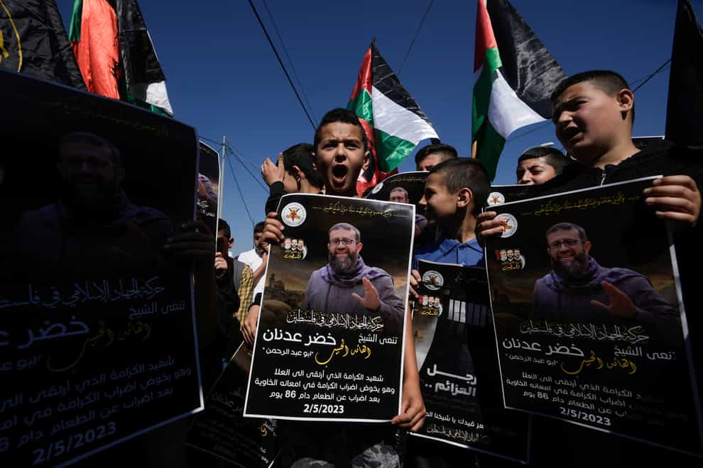 Palestinian children wave their national flag and hold posters showing Khader Adnan (Majdi Mohammed/AP)
