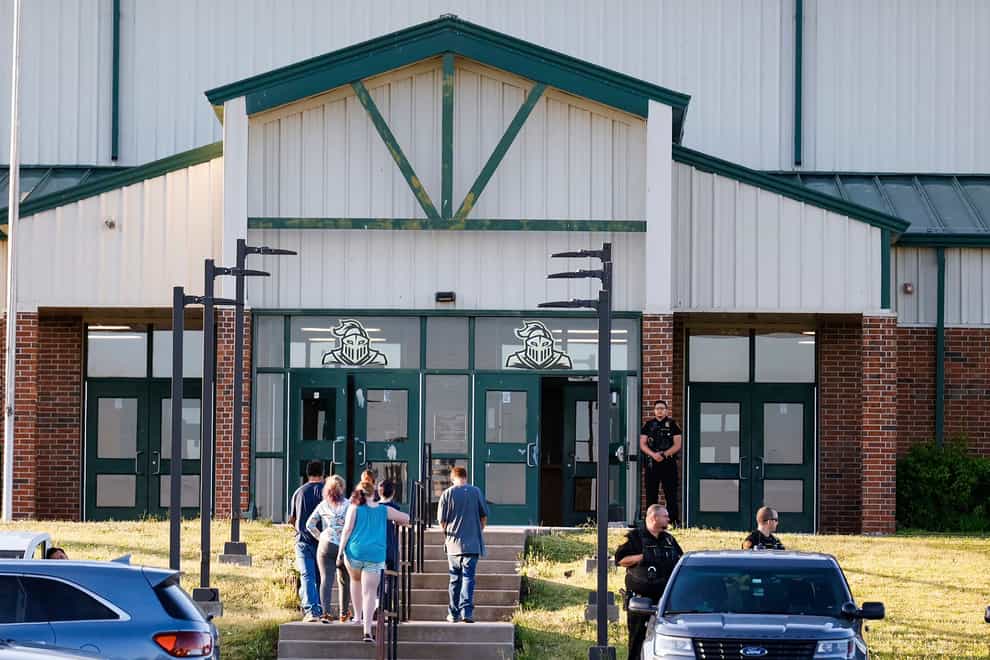 Law enforcement stand outside of Henryetta High School as people arrive for a vigil after Okmulgee County Sheriff reported seven people dead after a search for two missing teenage girls (The Oklahoman via AP)