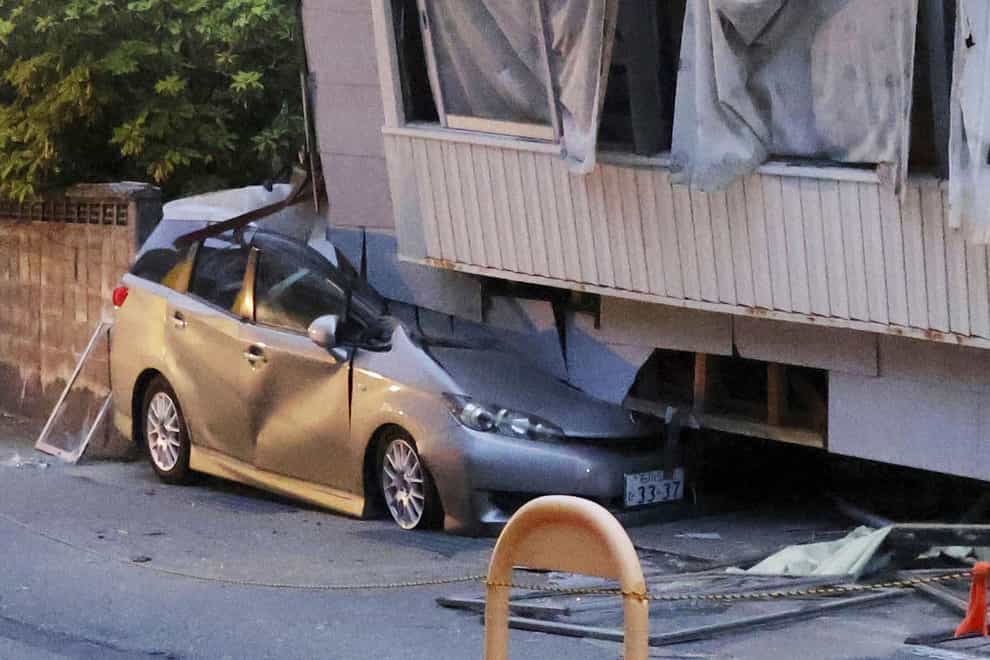 A car is seen crushed by a collapsed house after a strong earthquake in Suzu city, Ishikawa prefecture (Kyodo News via AP)
