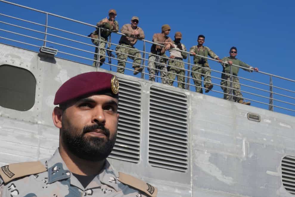 A Saudi officer stands alert as American naval soldiers monitor on the USNS Brunswick carrying evacuees from Sudan at Jeddah port, Saudi Arabia (Amr Nabil/AP/PA)