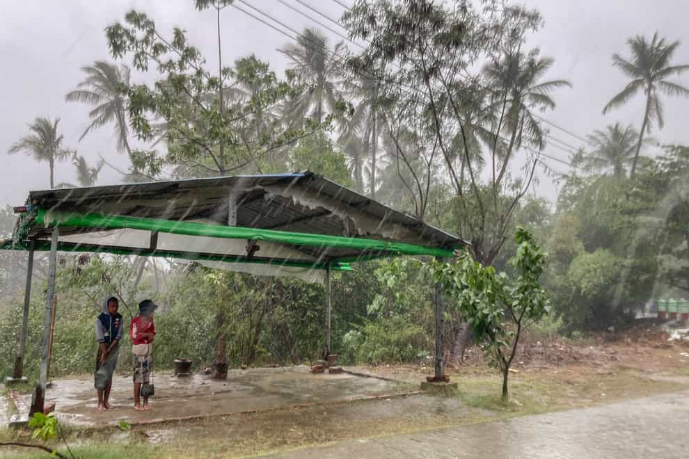 Two children stand under a shelter as rain from Cyclone Mocha batters down in Sittwe, Rakhine state (AP)