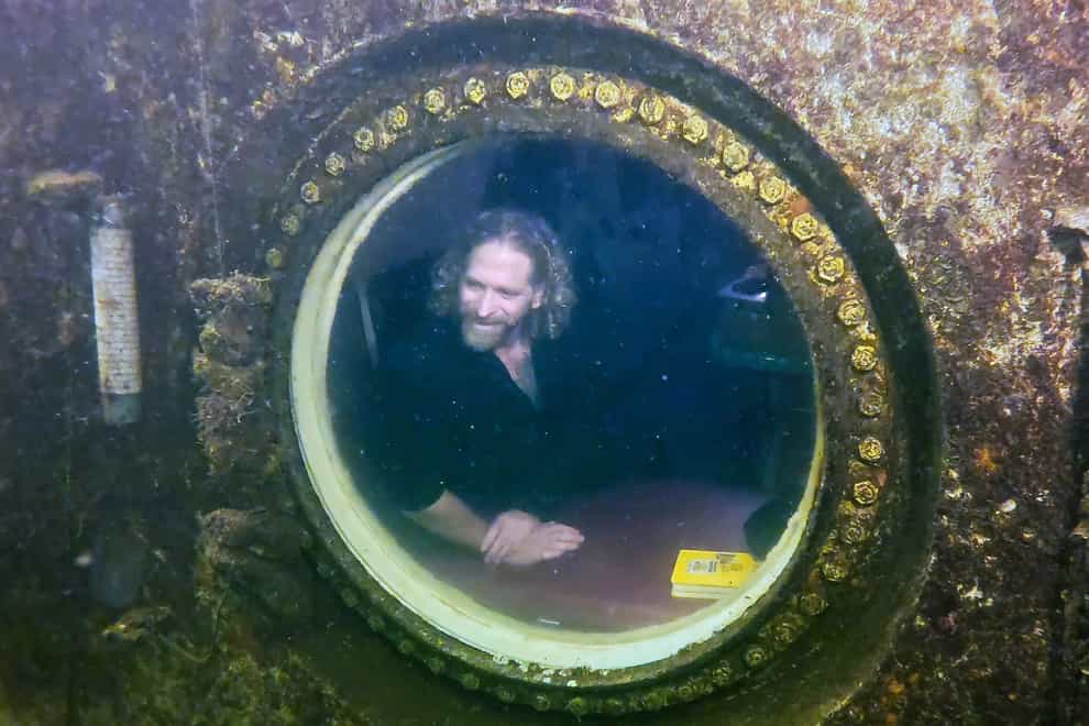 Diving explorer and medical researcher Dr Joseph Dituri peers out of a large porthole at Jules’ Undersea Lodge positioned at the bottom of a 30ft-deep lagoon in Key Largo, Florida (Frazier Nivens/Florida Keys News Bureau via AP)