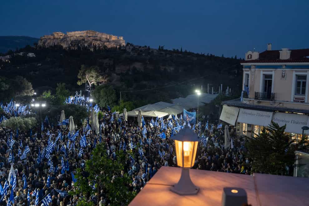 New Democracy party supporters wave Greek flags asPrime Minister and New Democracy leader Kyriakos Mitsotakis speaks during his main election campaign rally in Athens (Petros Giannakouris/AP)