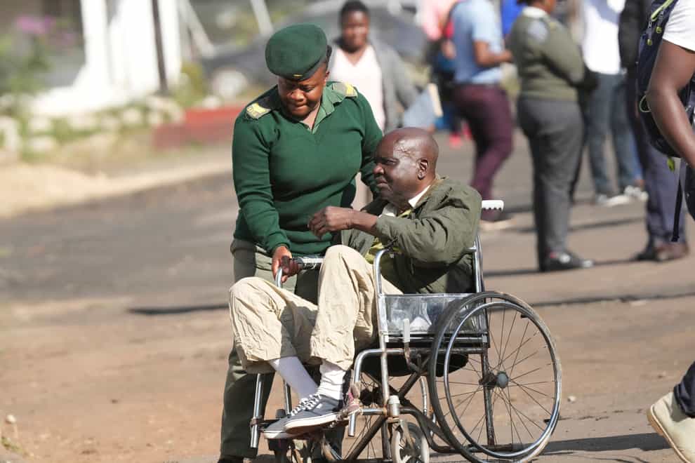 A prison officer escorts an elderly prisoner in a wheelchair after he was released from Harare Central Prison (Tsvangirayi Mukwazhi/AP)